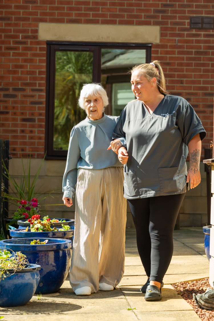 A resident and carer walking in the garden