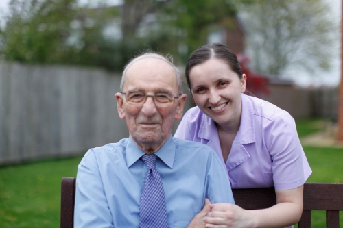 A carer and an older man posing for a photo and smiling