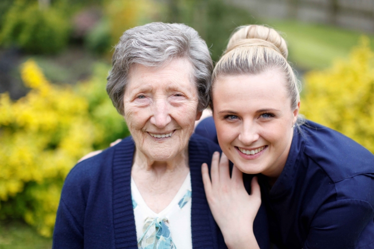 A carer and an older woman hugging and smiling for a photo