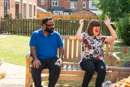 A carer and a resident laughing on a bench